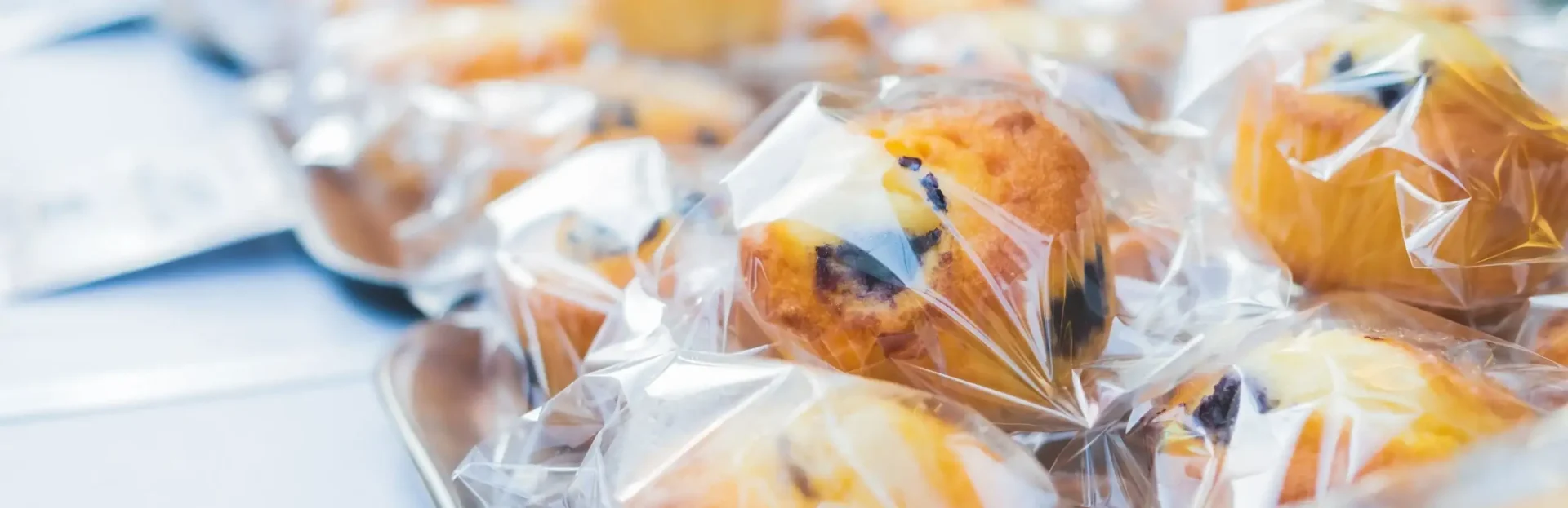page backgroun image of muffins in plastic packaging wrap